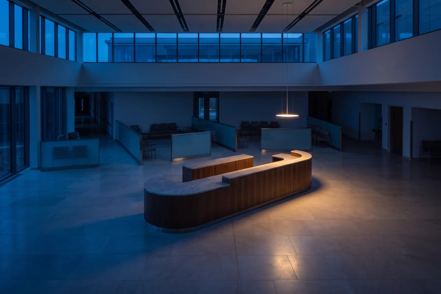 A hospital outpatient floor at blue hour, the waiting zones empty and the reception desk lit.