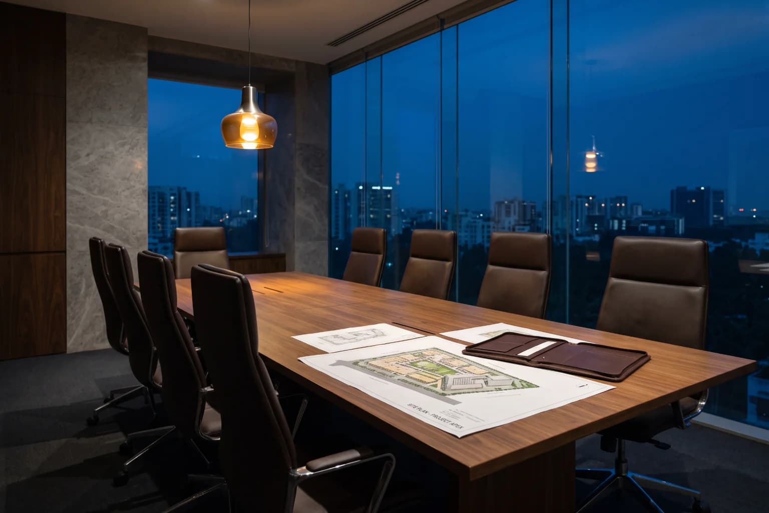 An advisory meeting room at blue hour with site plans open on a long table under one pendant.